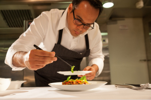 An image of a chef platting food in the kitchen - fine dining sop